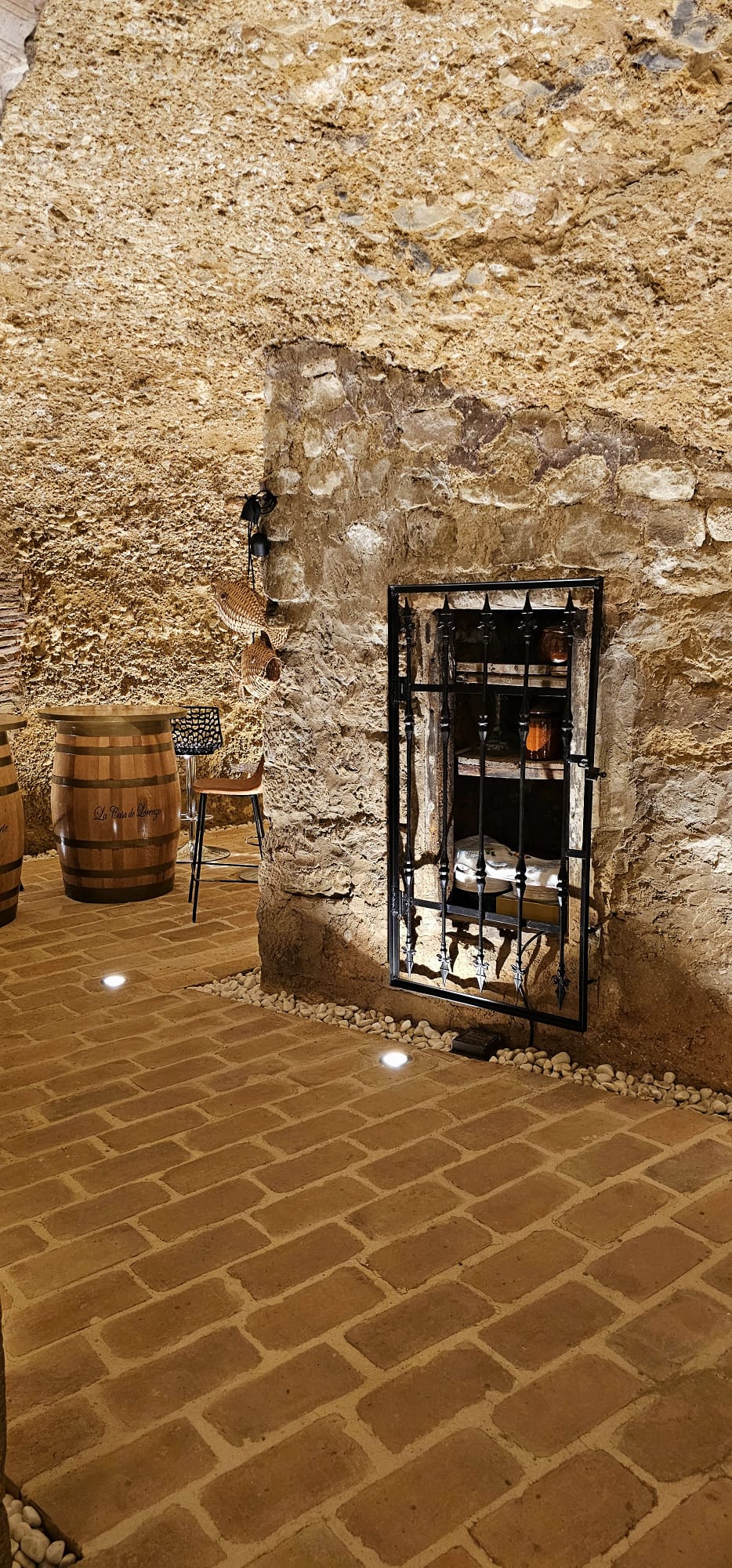 legado de ugarte alojamientos rurales bodega cueva reja hornacina laguardia - Legado de Ugarte ofrece casas rurales y apartamentos con encanto en Laguardia, corazón de la Rioja Alavesa. Dispones de casa rural por habitaciones en la Calle Mayor y alojamientos de alquiler íntegro con jardín y barbacoa, ideales para parejas, familias y grupos que quieren disfrutar de enoturismo y del casco histórico medieval. Habitaciones y apartamentos amplios, con baño privado, WiFi y todas las comodidades para una estancia tranquila entre viñedos. Tu alojamiento rural en Laguardia para conocer bodegas, rutas del vino y los pueblos más bonitos de Rioja Alavesa. Bodega cueva de piedra con reja y mesas de barrica en alojamientos rurales.